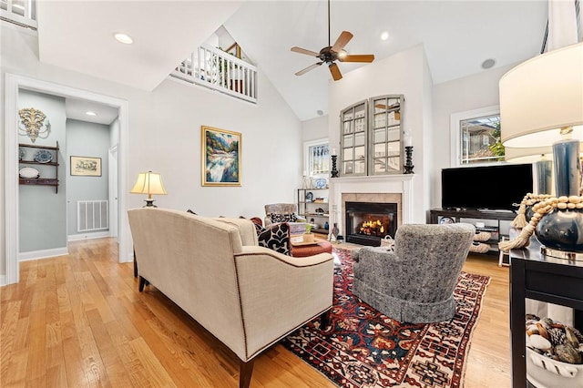 living room with ceiling fan, high vaulted ceiling, and light hardwood / wood-style floors