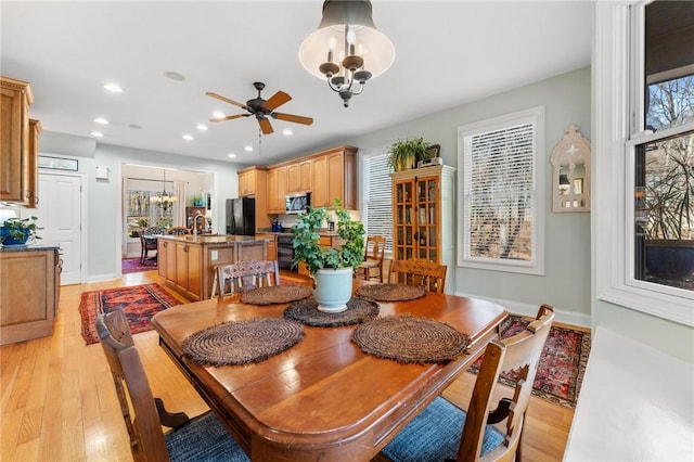 dining area with ceiling fan with notable chandelier and light hardwood / wood-style floors