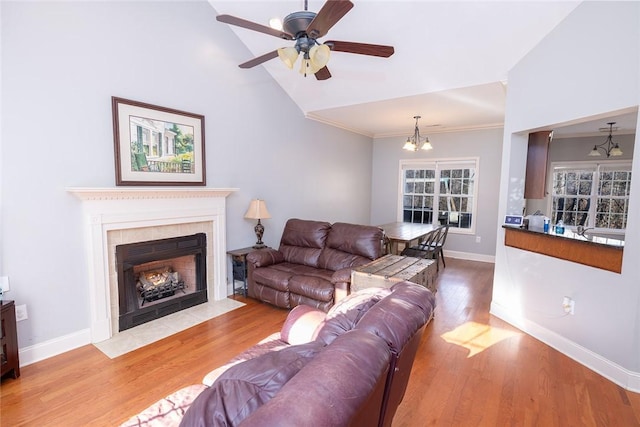 living room with ornamental molding, high vaulted ceiling, ceiling fan with notable chandelier, and light wood-type flooring