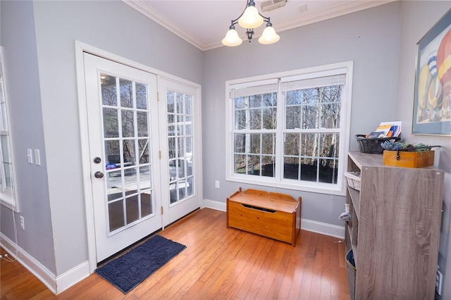 doorway to outside with ornamental molding, a chandelier, and hardwood / wood-style floors