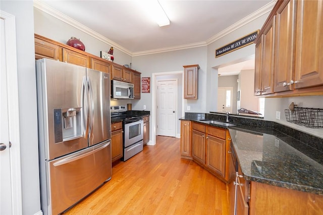 kitchen featuring sink, dark stone counters, stainless steel appliances, crown molding, and light wood-type flooring