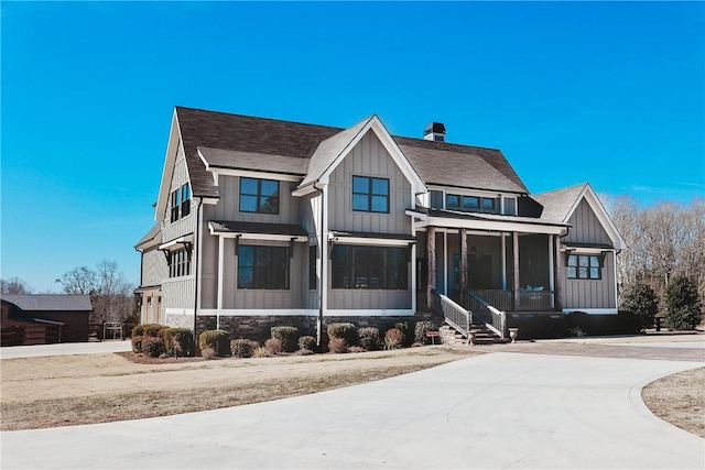 modern inspired farmhouse featuring board and batten siding, stone siding, a shingled roof, and a chimney