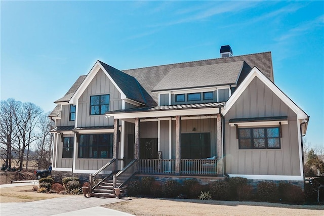 modern farmhouse style home featuring metal roof, covered porch, board and batten siding, a standing seam roof, and a chimney