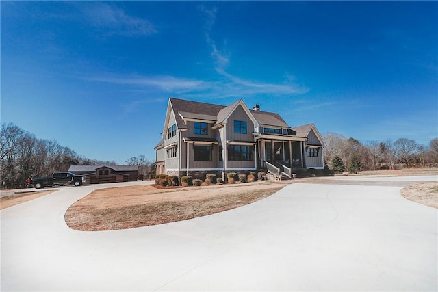 view of front of house with driveway, a chimney, and board and batten siding