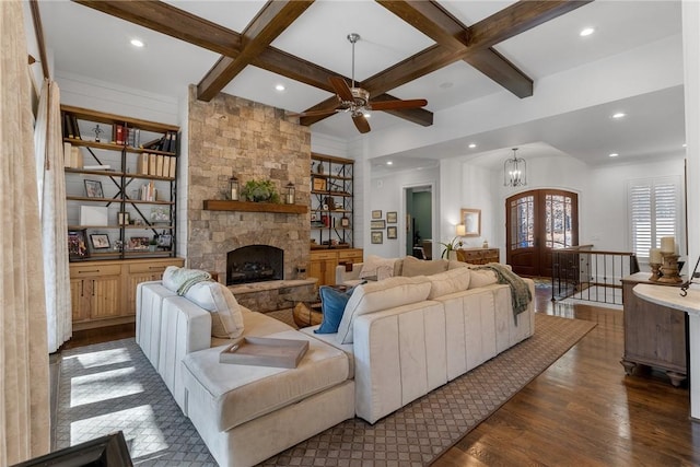 living room featuring coffered ceiling, dark hardwood / wood-style flooring, a stone fireplace, and beamed ceiling