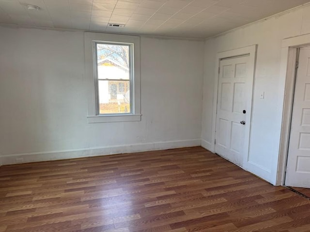 unfurnished bedroom with dark hardwood / wood-style flooring and crown molding