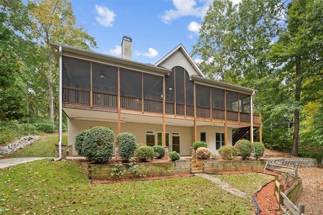 rear view of house featuring a sunroom, a chimney, and a yard