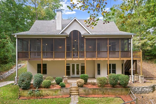 rear view of house featuring a patio, a sunroom, a chimney, stairs, and french doors