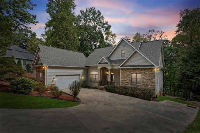 view of front of house featuring a shingled roof, stone siding, an attached garage, and concrete driveway