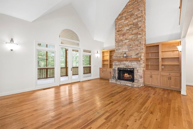 unfurnished living room featuring light wood-style floors, a fireplace, high vaulted ceiling, and baseboards