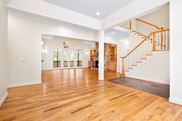 unfurnished living room featuring decorative columns, stairway, and wood finished floors