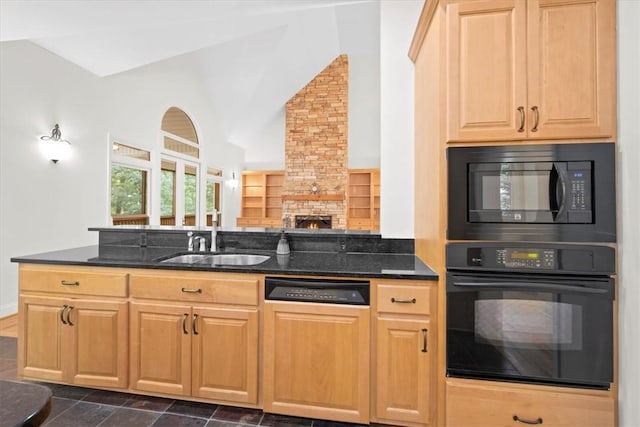 kitchen featuring a stone fireplace, a sink, vaulted ceiling, black appliances, and dark stone countertops