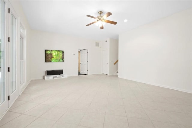 empty room featuring a barn door, visible vents, a ceiling fan, baseboards, and stairway