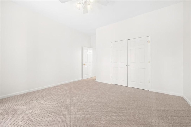 unfurnished bedroom with a closet, carpet, a ceiling fan, and baseboards