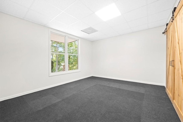 empty room with dark carpet, baseboards, and a barn door