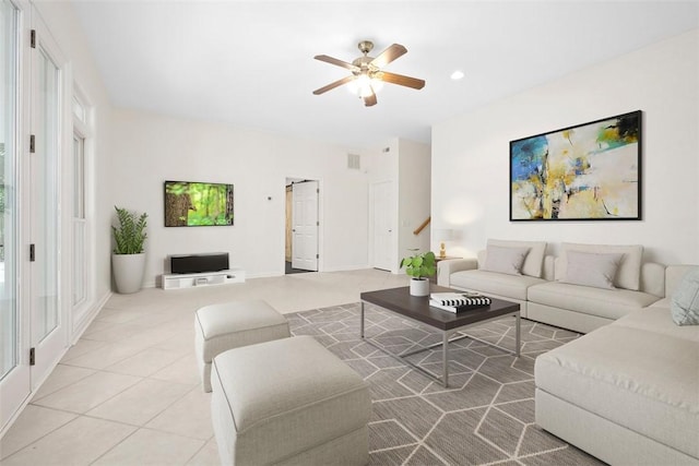 living room with light tile patterned floors, a barn door, visible vents, and a ceiling fan