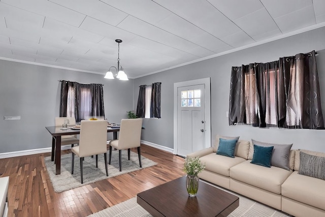 living room featuring a notable chandelier, ornamental molding, and hardwood / wood-style floors