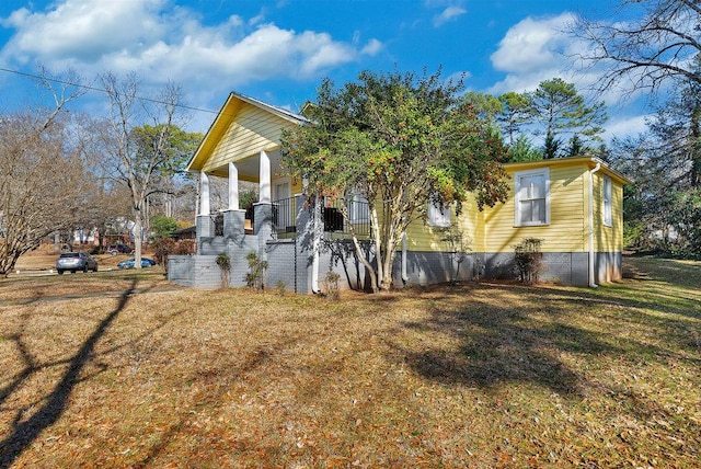 view of side of home featuring a porch and a lawn