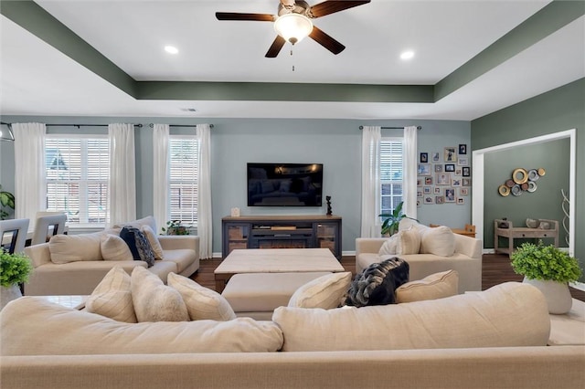 living room with ceiling fan, a raised ceiling, and hardwood / wood-style floors