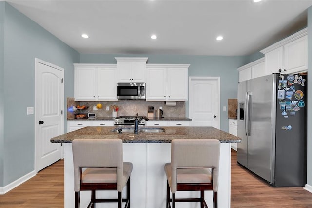 kitchen featuring white cabinets, appliances with stainless steel finishes, sink, and a kitchen island with sink