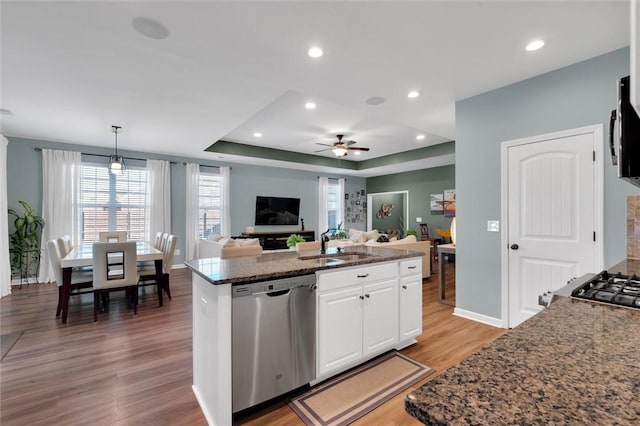 kitchen with sink, white cabinetry, decorative light fixtures, stainless steel dishwasher, and a kitchen island with sink