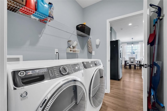 clothes washing area with washing machine and dryer and wood-type flooring