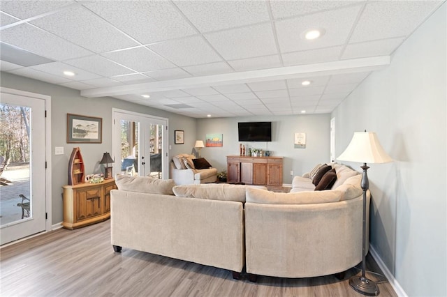 living room with french doors, a healthy amount of sunlight, light hardwood / wood-style floors, and a drop ceiling