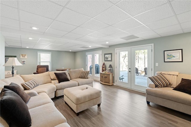 living room with a drop ceiling, hardwood / wood-style floors, and french doors