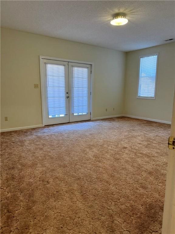 carpeted empty room featuring a textured ceiling and french doors