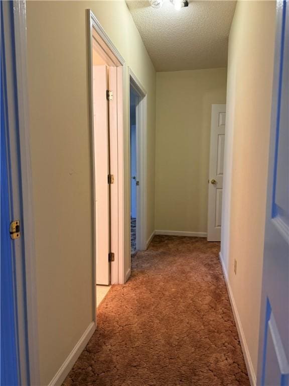 hallway with light carpet and a textured ceiling