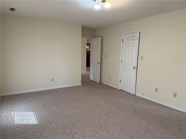 carpeted empty room with a textured ceiling