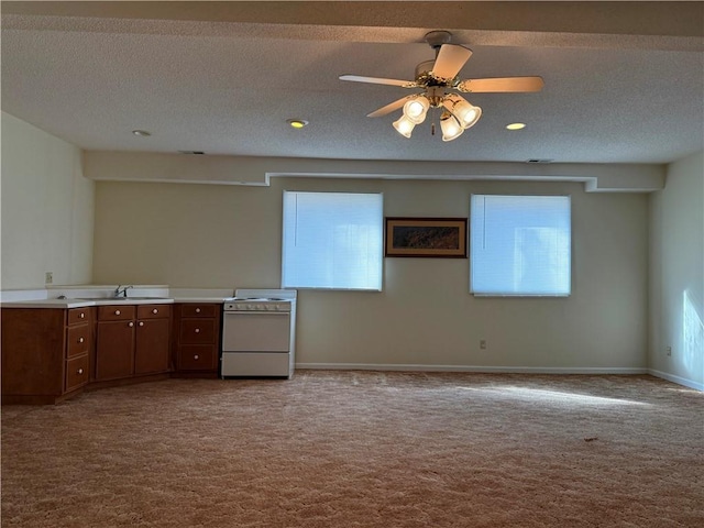 kitchen with ceiling fan, range, light colored carpet, and a textured ceiling