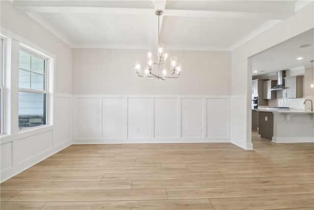 unfurnished dining area featuring ornamental molding, a chandelier, and light wood-type flooring