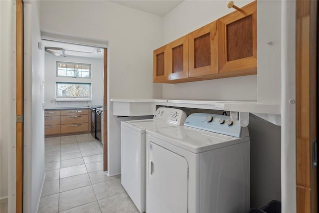 washroom with independent washer and dryer, light tile patterned floors, and cabinets