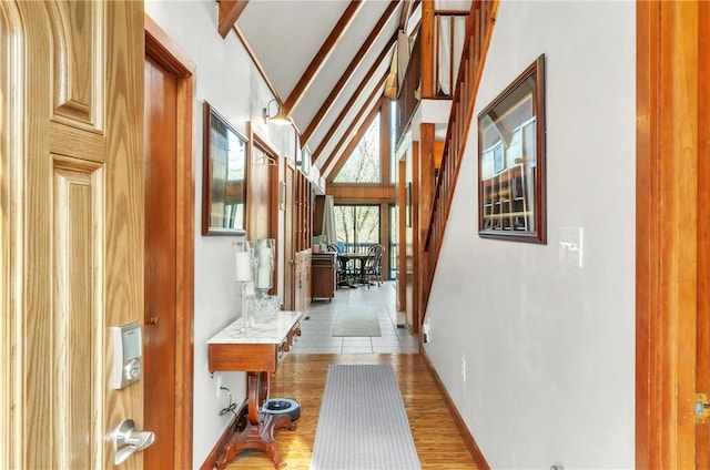 hall featuring beamed ceiling, high vaulted ceiling, and light hardwood / wood-style floors