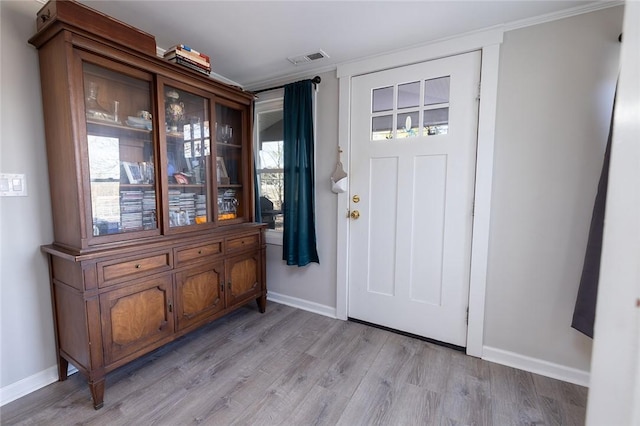 foyer entrance with ornamental molding and light wood-type flooring