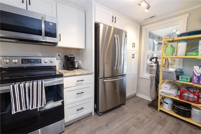 kitchen with stainless steel appliances, light stone counters, white cabinets, and light hardwood / wood-style floors