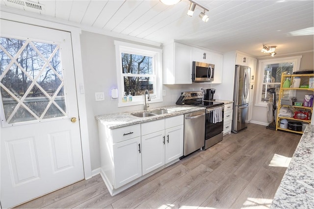 kitchen with sink, light hardwood / wood-style flooring, appliances with stainless steel finishes, light stone countertops, and white cabinets