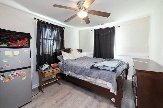 bedroom featuring ceiling fan, stainless steel fridge, and light hardwood / wood-style floors