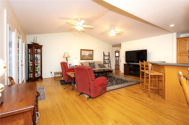 living room with ceiling fan, lofted ceiling, and light hardwood / wood-style flooring