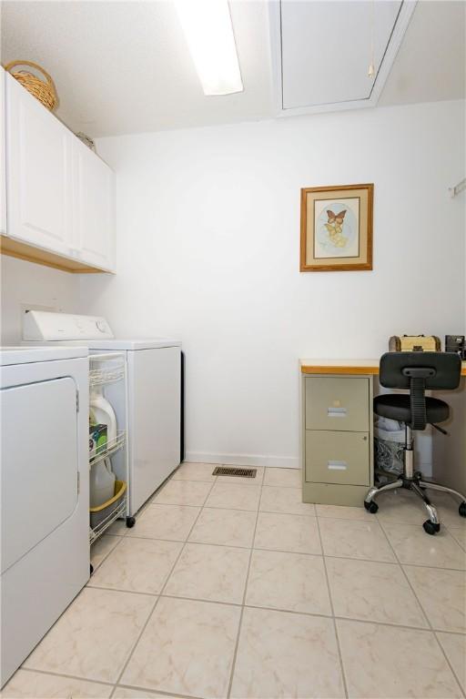 washroom featuring light tile patterned floors, cabinets, and washing machine and clothes dryer