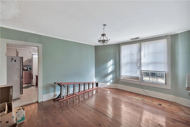 unfurnished room with ornamental molding and light wood-type flooring