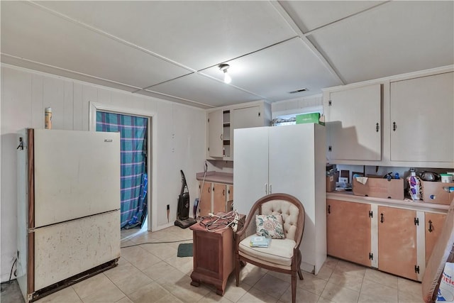 kitchen with light tile patterned floors, white cabinets, and white fridge