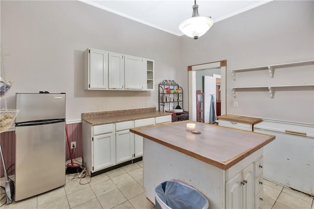 kitchen featuring pendant lighting, light tile patterned floors, stainless steel fridge, white cabinetry, and a kitchen island