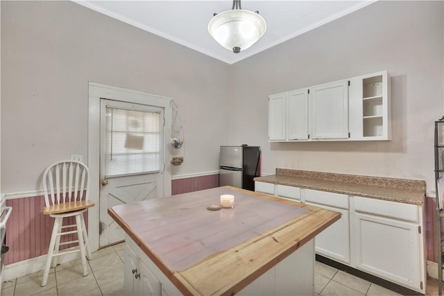 kitchen with white cabinets, light tile patterned floors, stainless steel fridge, and decorative light fixtures