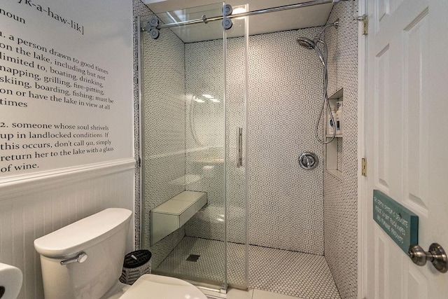 bathroom featuring a shower with door and toilet