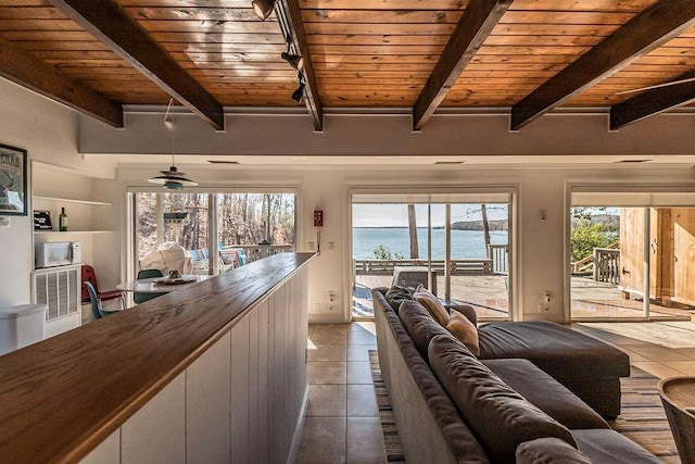 living room featuring a water view, wood ceiling, tile patterned flooring, and beamed ceiling