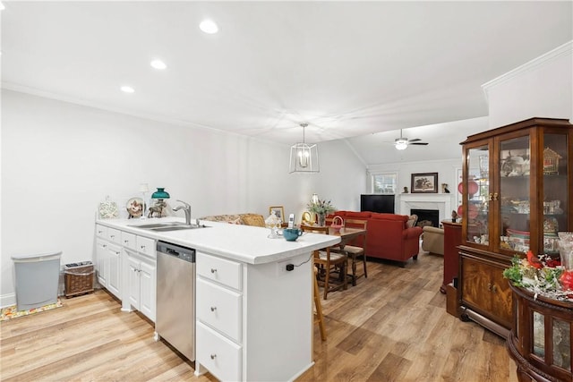 kitchen with sink, a breakfast bar area, hanging light fixtures, dishwasher, and white cabinets