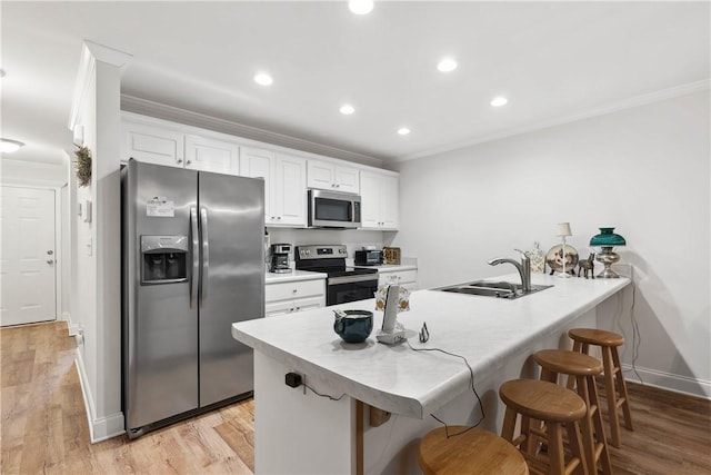 kitchen featuring stainless steel appliances, white cabinetry, crown molding, and a kitchen bar