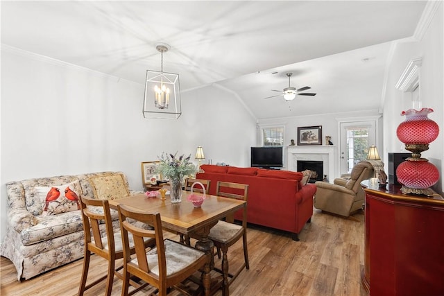 dining room with lofted ceiling, ornamental molding, and light wood-type flooring